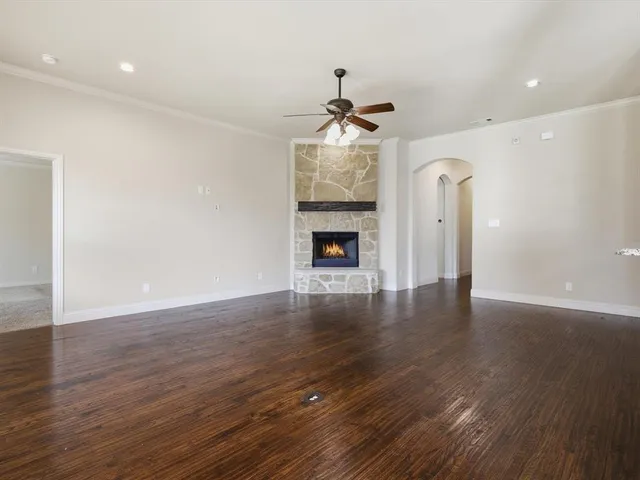 a view of an empty room with wooden floor fireplace and a window