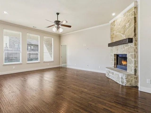 a view of an empty room with wooden floor fireplace and a window