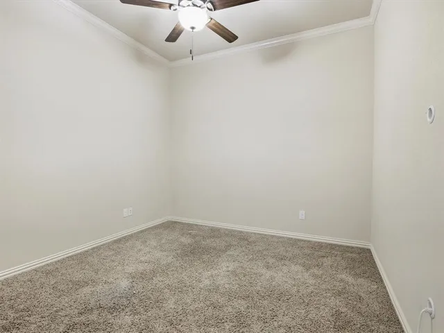 an empty room with a chandelier fan and windows