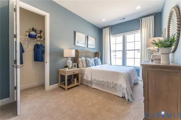 a bed sitting in a spacious bedroom next to a window and a flat screen tv