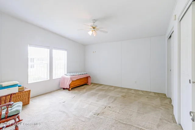 an empty room with windows and ceiling fan