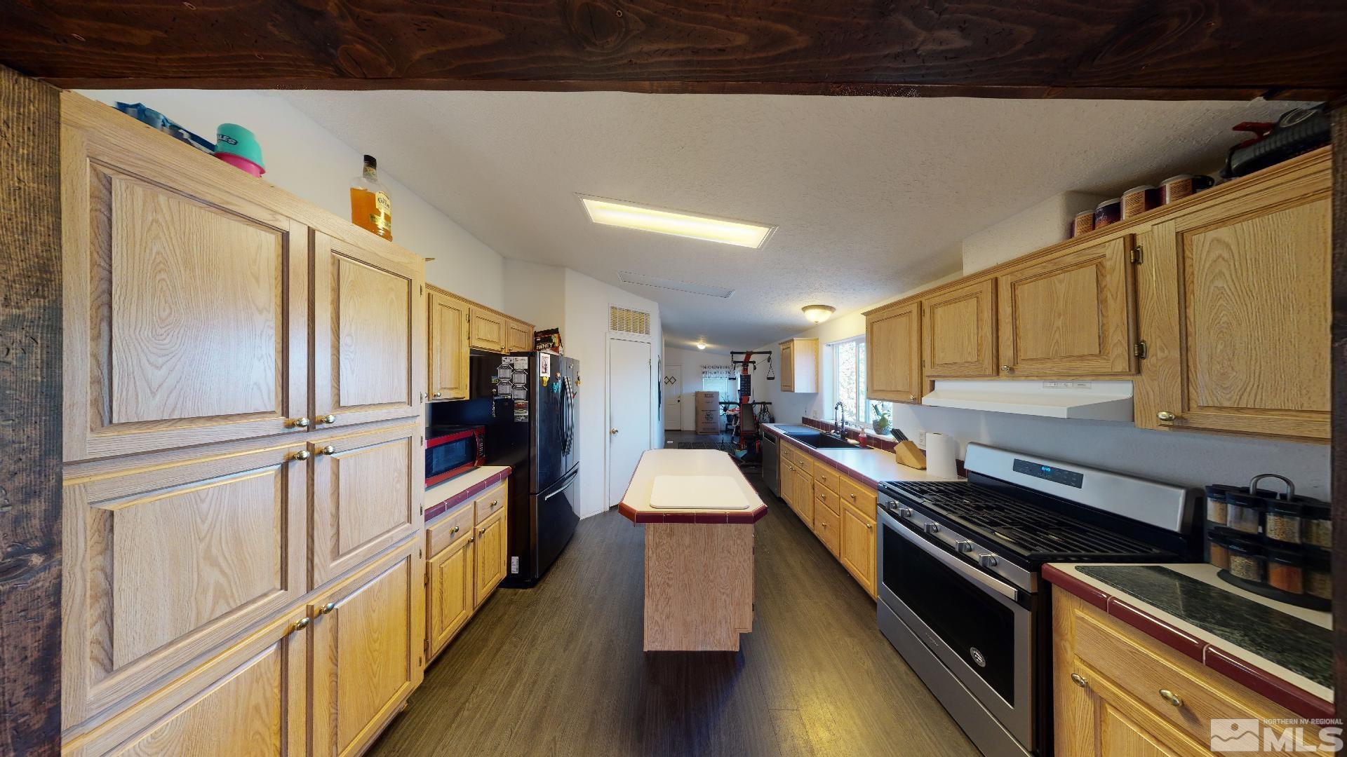 230 Danforth Drive Sun Valley, NV 89433 - Photo 11 of 28 a kitchen with stainless steel appliances a stove a refrigerator white cabinets and wooden floor