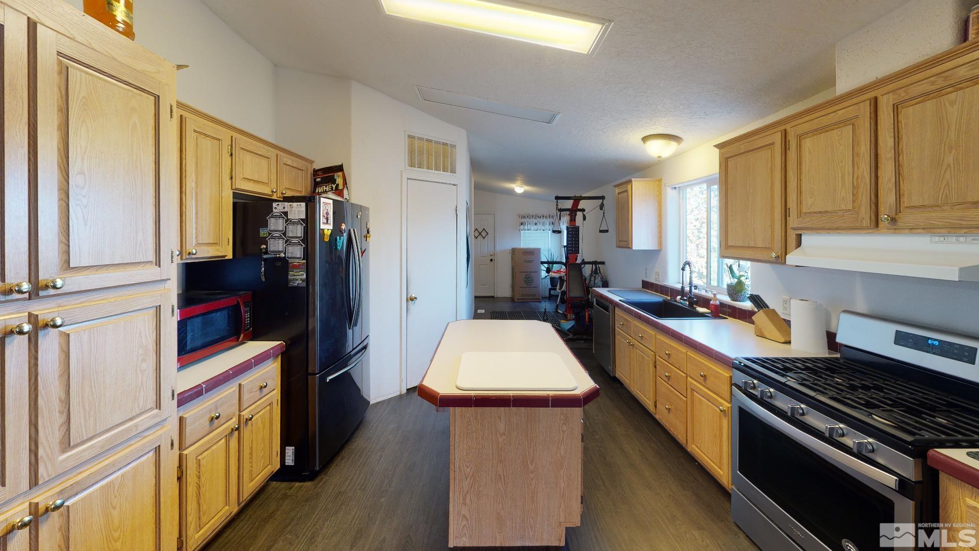 230 Danforth Drive Sun Valley, NV 89433 - Photo 12 of 28 a kitchen with stainless steel appliances sink stove refrigerator and cabinets