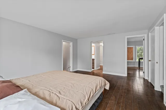 a bedroom with a bed a couch and wooden floor