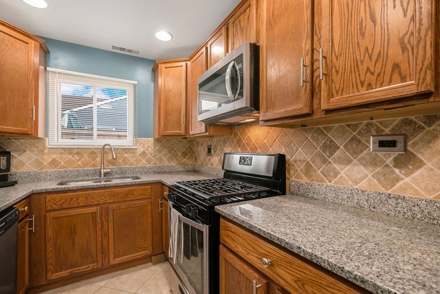 172 Oxford Road Bolingbrook, IL 60440 - Photo 7 of 27 a kitchen with stainless steel appliances granite countertop a sink stove and microwave