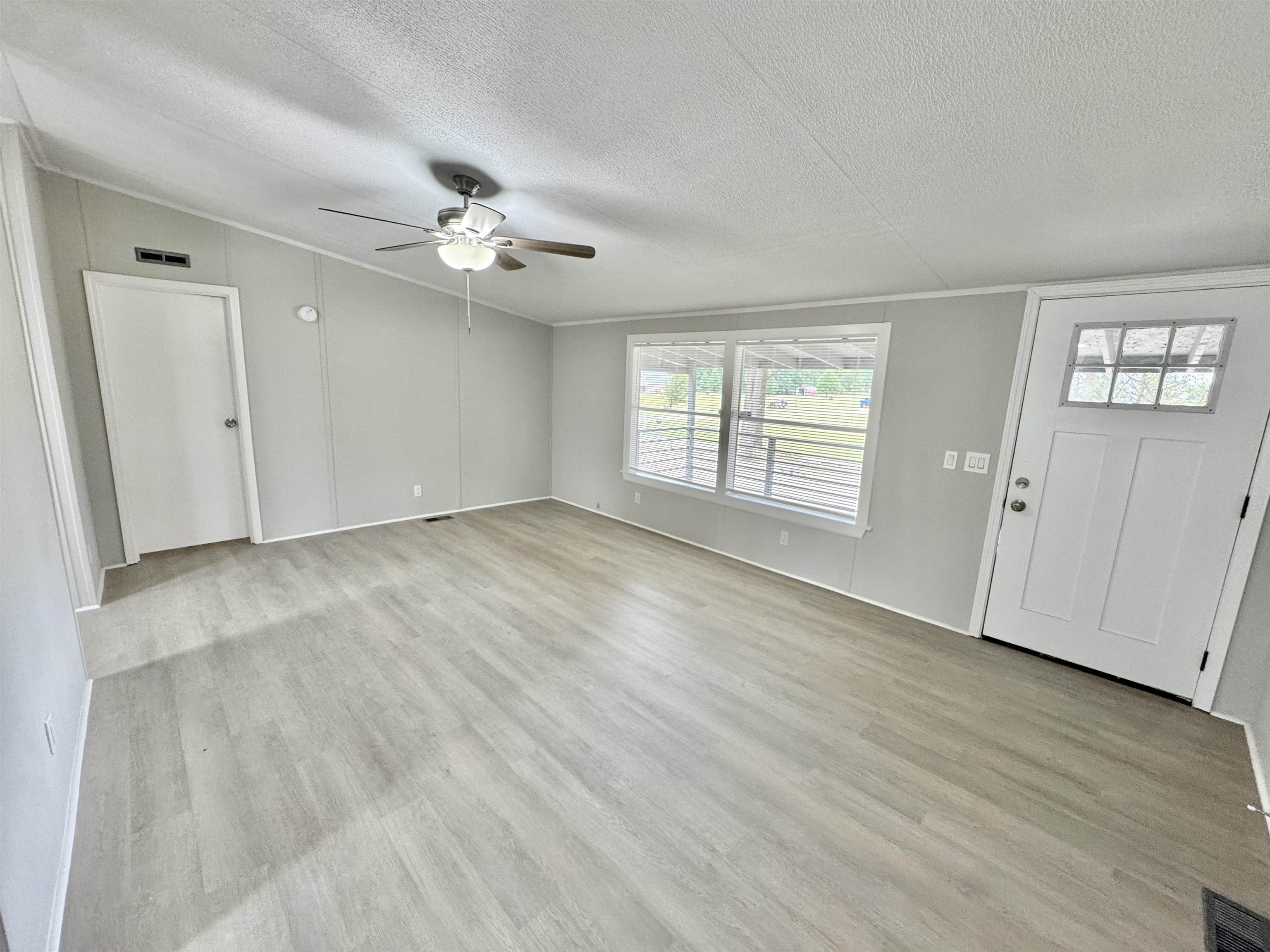 3178 Portersville Road Atoka, TN 38004 - Photo 12 of 31 an empty room with wooden floor ceiling fan and windows