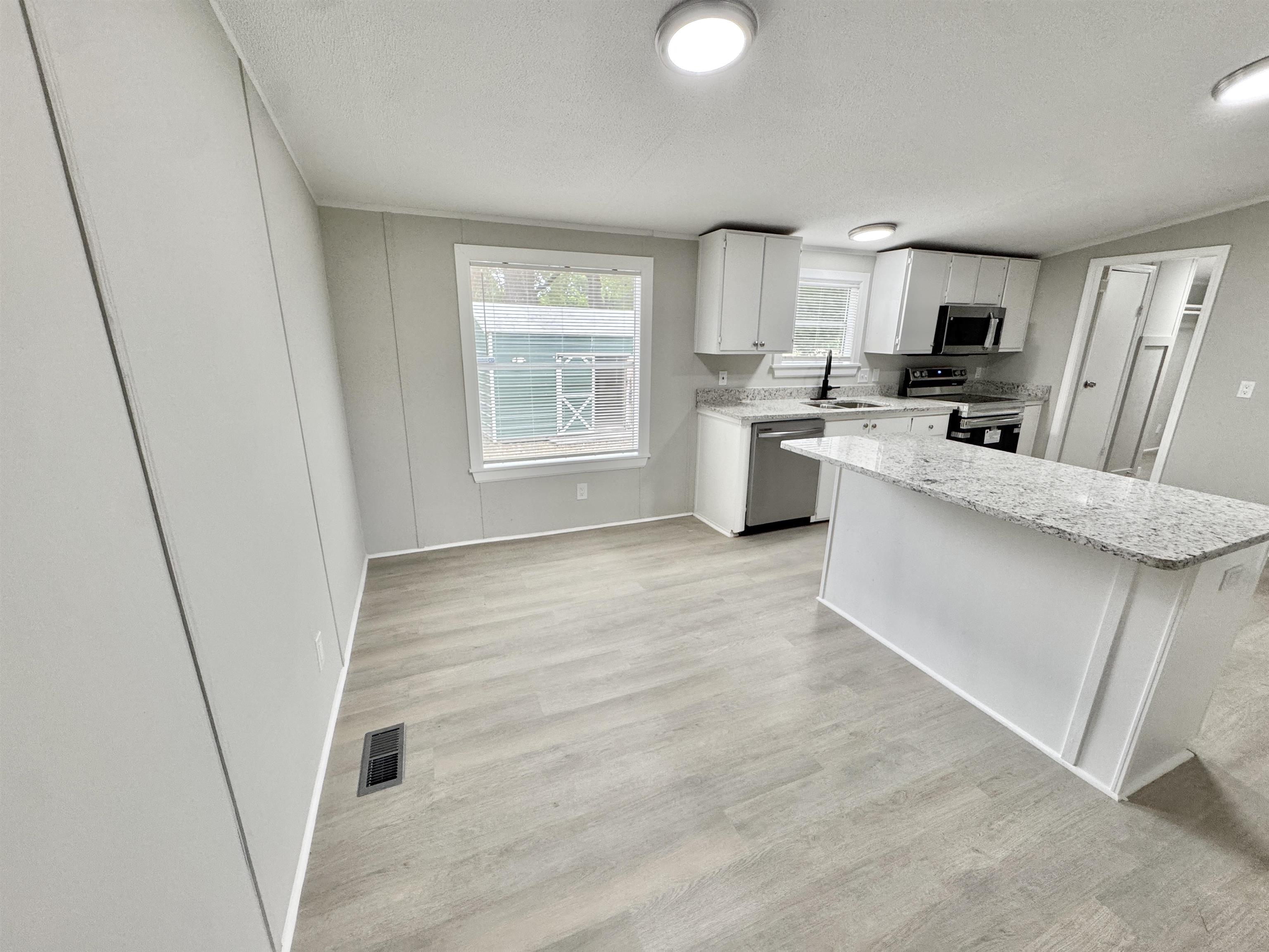 3178 Portersville Road Atoka, TN 38004 - Photo 8 of 31 a large white kitchen with stainless steel appliances granite countertop a refrigerator a sink a stove a microwave a counter space and cabinets