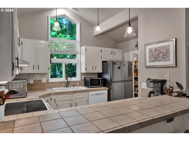 a kitchen with a refrigerator a stove a sink a window and a counter top space