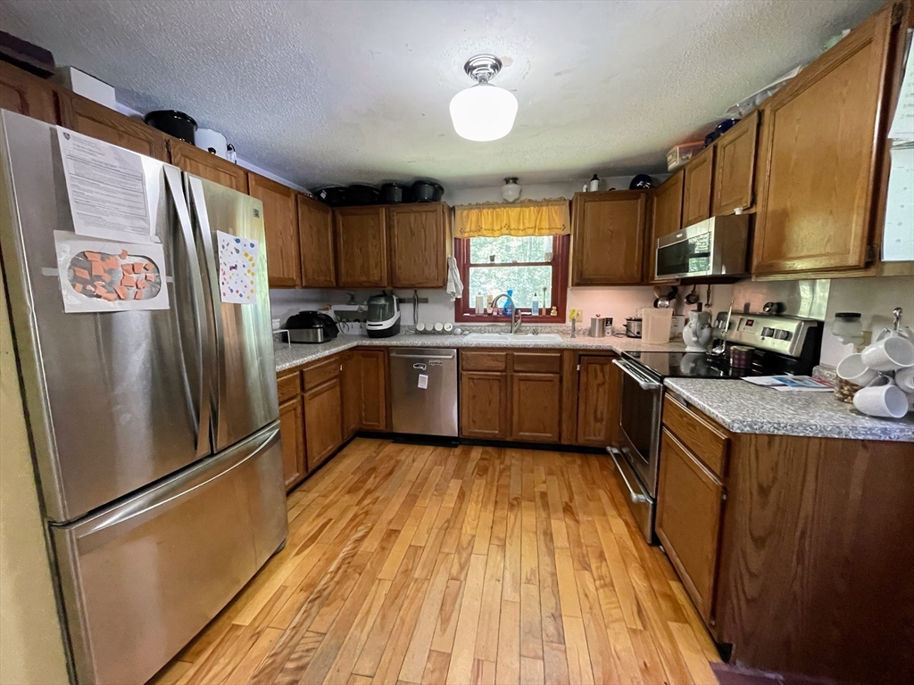 330 Arbor Street Lunenburg, MA 01462 - Photo 7 of 33 a kitchen with stainless steel appliances granite countertop a refrigerator a sink dishwasher a stove with wooden floor and cabinets
