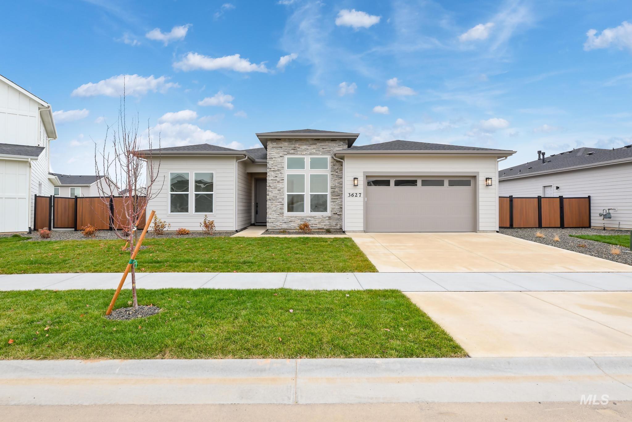 Prairie-style house featuring an attached garage, driveway, and stone siding