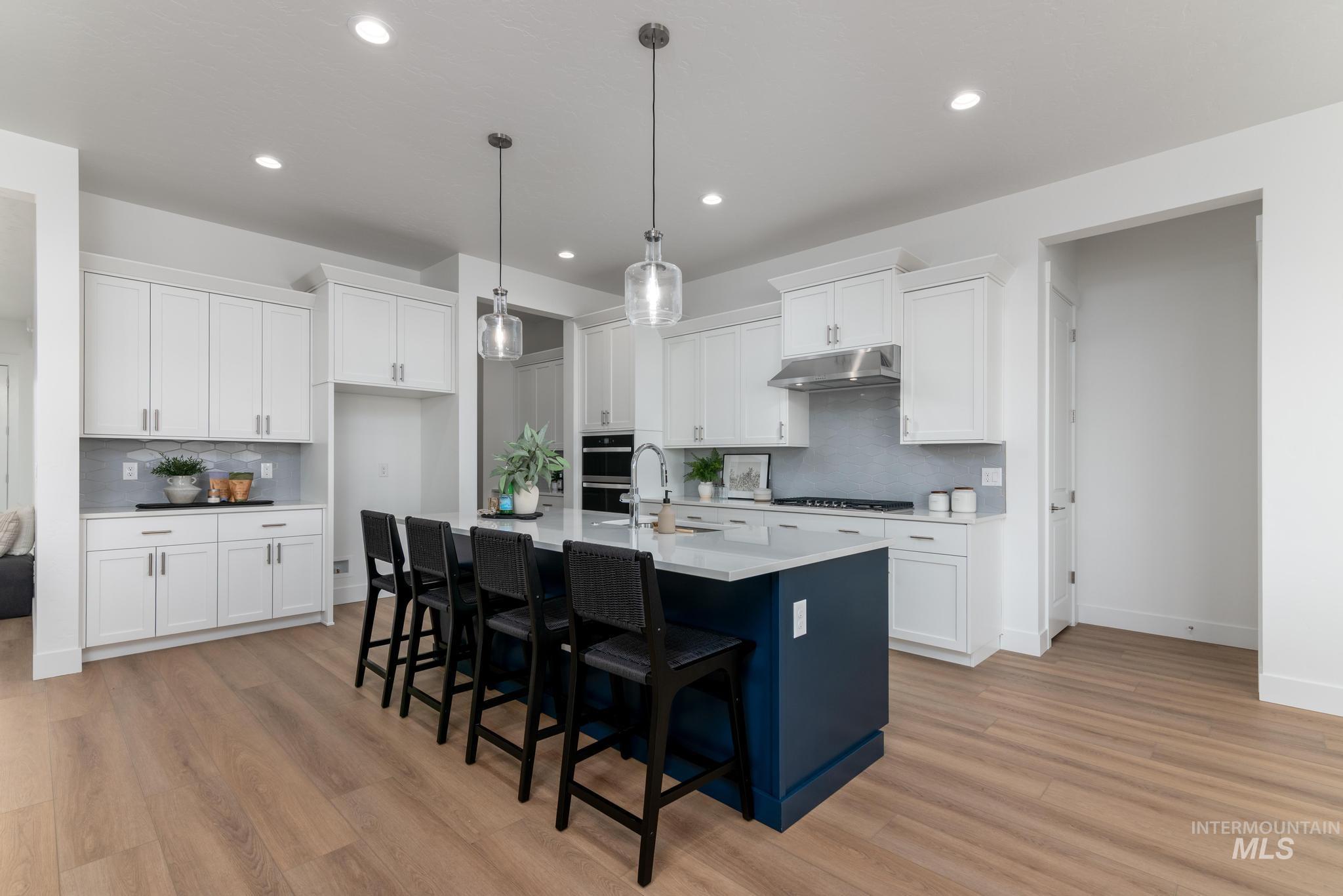 3612 North Pindall Way Star, ID 83669 - Photo 5 of 12 Kitchen featuring a breakfast bar area, two tone color scheme, an island with sink, light wood-type flooring, and decorative light fixtures