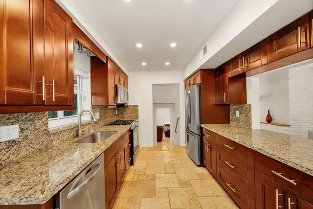 a large kitchen with stainless steel appliances granite countertop a sink and cabinets