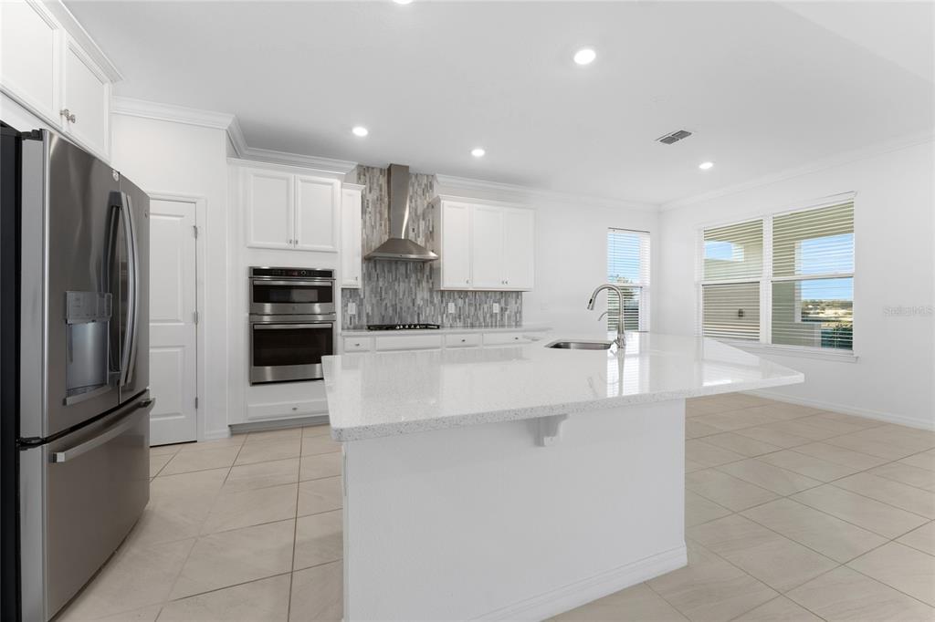 2834 High Pointe Circle Clermont, FL 34711 - Photo 8 of 39 a large kitchen with stainless steel appliances a refrigerator a sink a stove and white cabinets