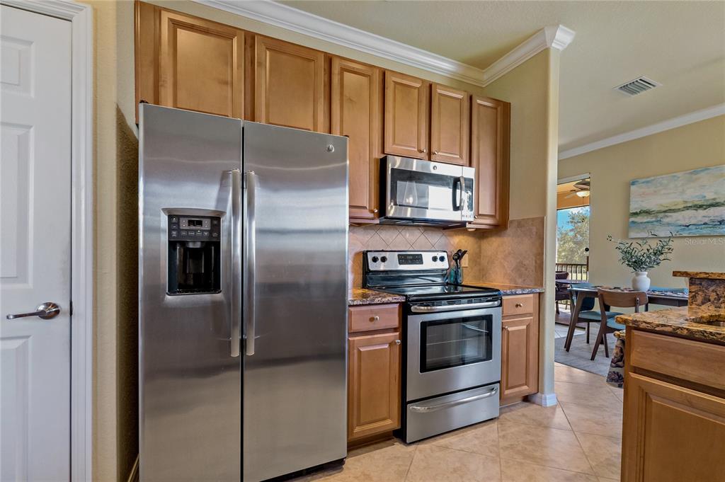 7015 Grand Estuary Trail, Unit 103 Bradenton, FL 34212 - Photo 30 of 62 a kitchen with stainless steel appliances granite countertop a refrigerator stove and oven