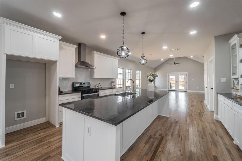 a large kitchen with granite countertop a large center island a sink stainless steel appliances and cabinets