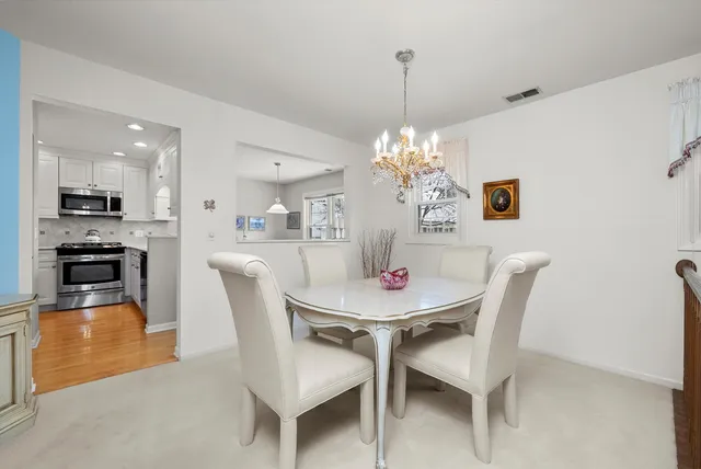 a dining room with furniture a chandelier and kitchen view