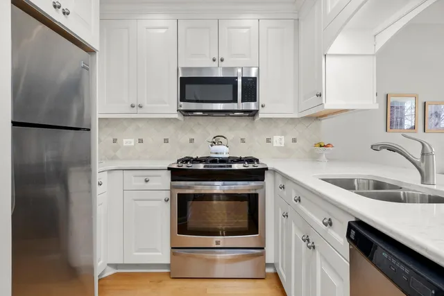 a kitchen with granite countertop white cabinets and stainless steel appliances