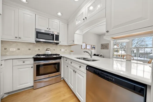 a kitchen with stainless steel appliances white cabinets a sink and a stove