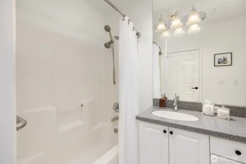 a bathroom with a granite countertop sink a mirror and a shower