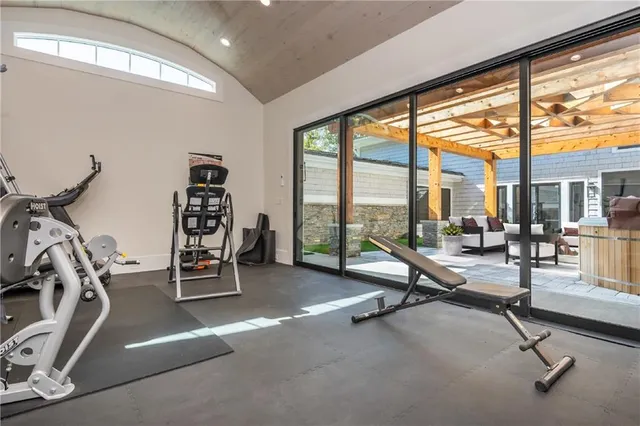 a view of a patio with couches table and chairs under an umbrella with a small yard