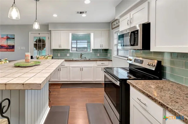 a kitchen with a sink stove top oven and microwave