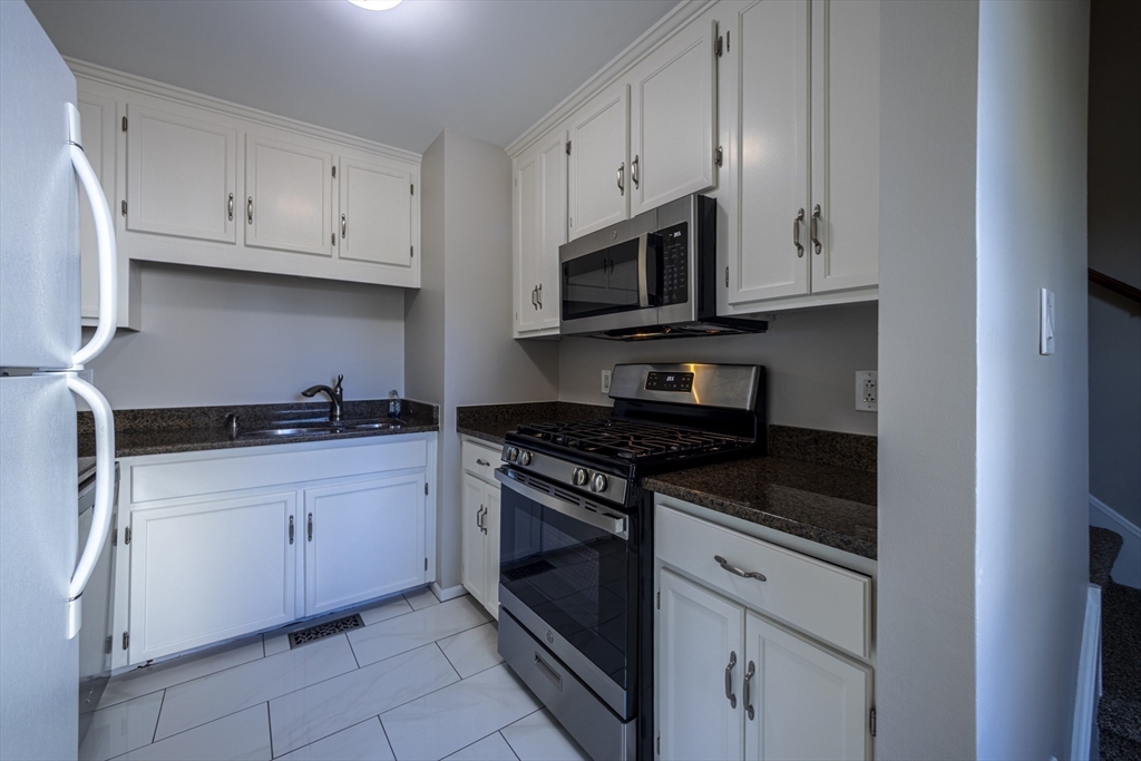 357 Boylston Street, Unit 3 Lowell, MA 01852 - Photo 9 of 35 a kitchen with stainless steel appliances granite countertop grey cabinets a stove a sink and dishwasher