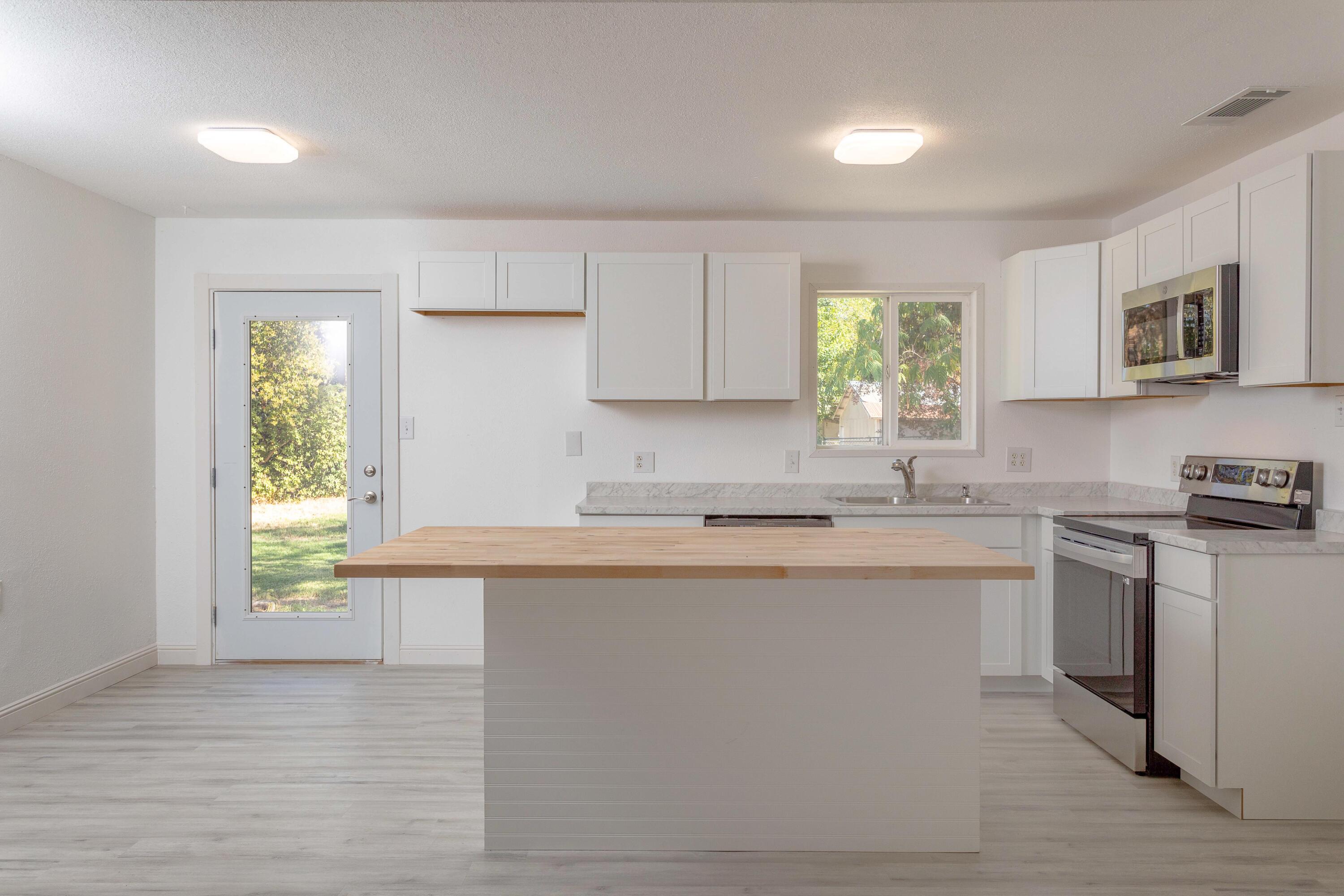 2943 Kenco Avenue Redding, CA 96002 - Photo 4 of 19 a kitchen with stainless steel appliances granite countertop a sink and a stove next to a window