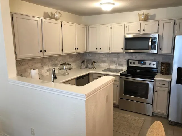 a kitchen with stainless steel appliances a stove a microwave and white cabinets