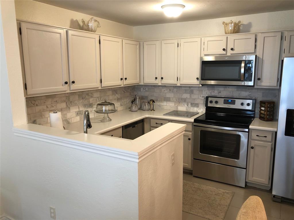 6108 Abrams Road, Unit 613 Dallas, TX 75231 - Photo 1 of 27 a kitchen with stainless steel appliances a stove a microwave and white cabinets