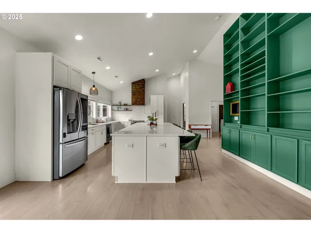 a kitchen with stainless steel appliances kitchen island a sink a refrigerator and a cabinets
