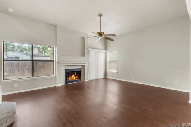 a view of empty room with wooden floor fireplace and window