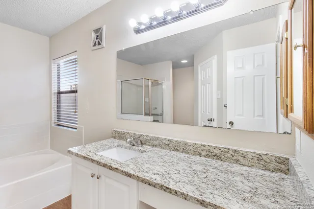 a bathroom with a granite countertop sink and a bathtub