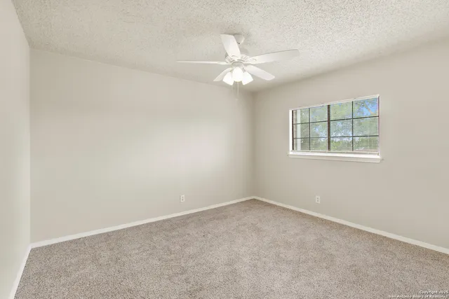 an empty room with a window and a fan