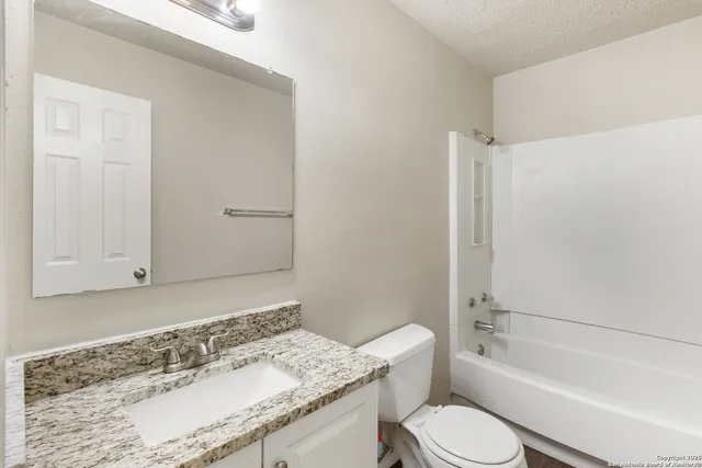 a bathroom with a granite countertop sink toilet a mirror and bathtub