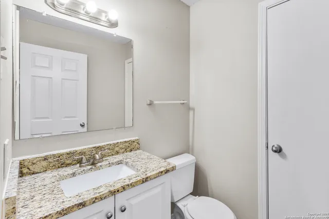 a bathroom with a granite countertop sink a toilet and mirror