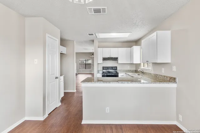 a large kitchen with stainless steel appliances granite countertop a sink a stove a refrigerator a center island and cabinets