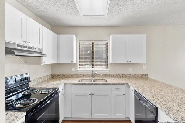 a kitchen with granite countertop a stove sink and cabinets