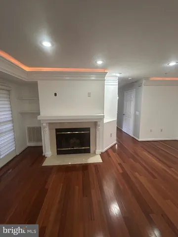 a view of an empty room with wooden floor fireplace and a window