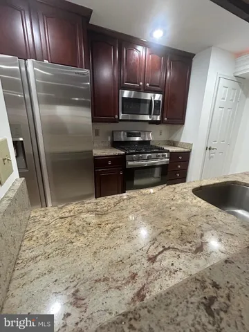 a kitchen with granite countertop a refrigerator and a sink