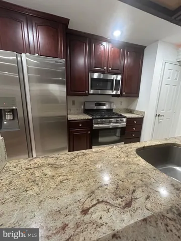 a kitchen with granite countertop stainless steel appliances and refrigerator