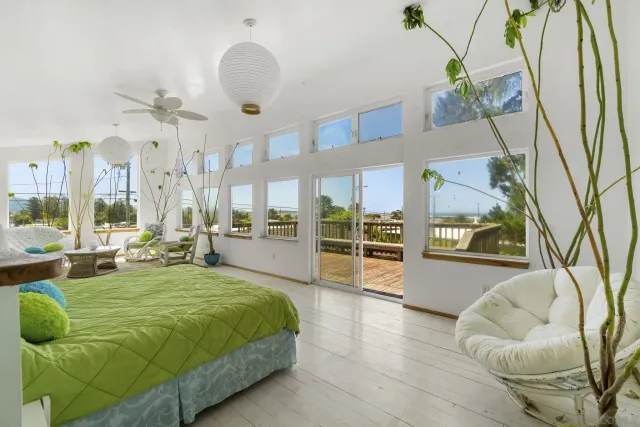 a large white bed sitting in a living room next to a window