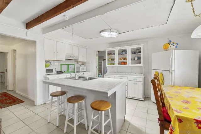 a kitchen with stainless steel appliances granite countertop a table chairs and a refrigerator