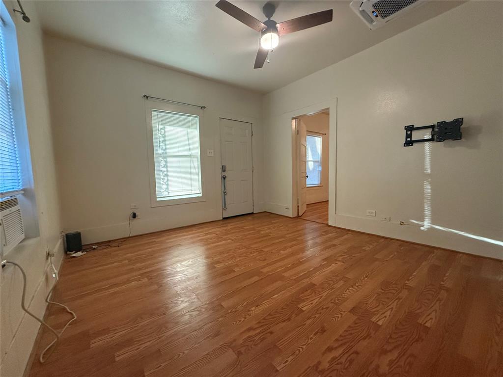 514 Ritchey Street Gainesville, TX 76240 - Photo 2 of 7 an empty room with wooden floor and windows