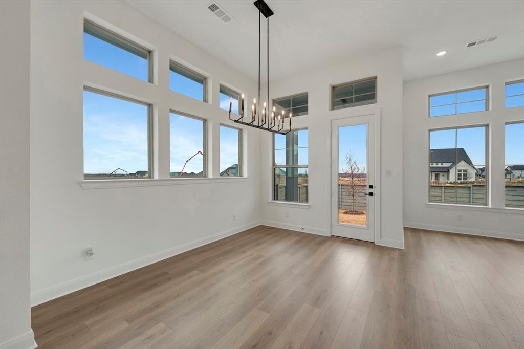 8712 Chestnut Lane Justin, TX 76247 - Photo 11 of 29 Unfurnished dining area with suspended lighting, dark wood-type flooring, plenty of natural light, and a high ceiling