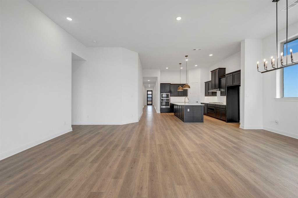 8712 Chestnut Lane Justin, TX 76247 - Photo 29 of 29 Kitchen featuring open floor plan, a center island with sink, light countertops, light wood-style flooring, and oven
