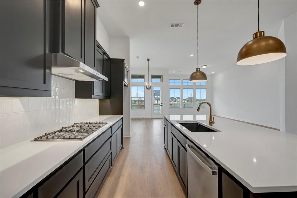 8712 Chestnut Lane Justin, TX 76247 - Photo 8 of 29 Kitchen with a spacious island, light wood finished floors, stainless steel appliances, pendant lighting, and decorative backsplash