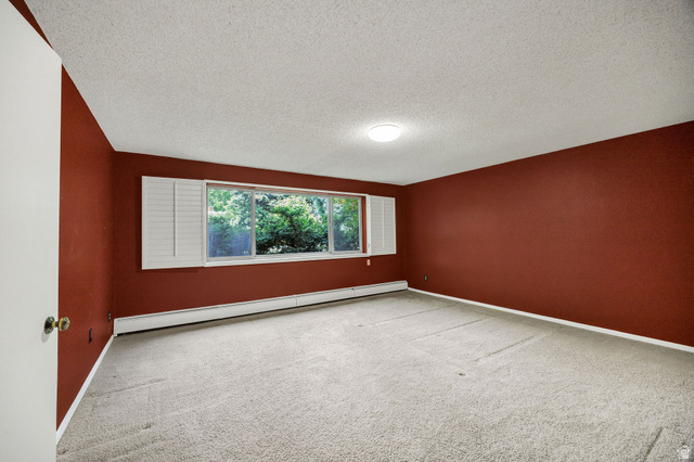 1365 Sumac Drive Logan, UT 84321 - Photo 35 of 66 Spacious room featuring a wide window with white plantation shutters, light-toned carpeting, and baseboard heating