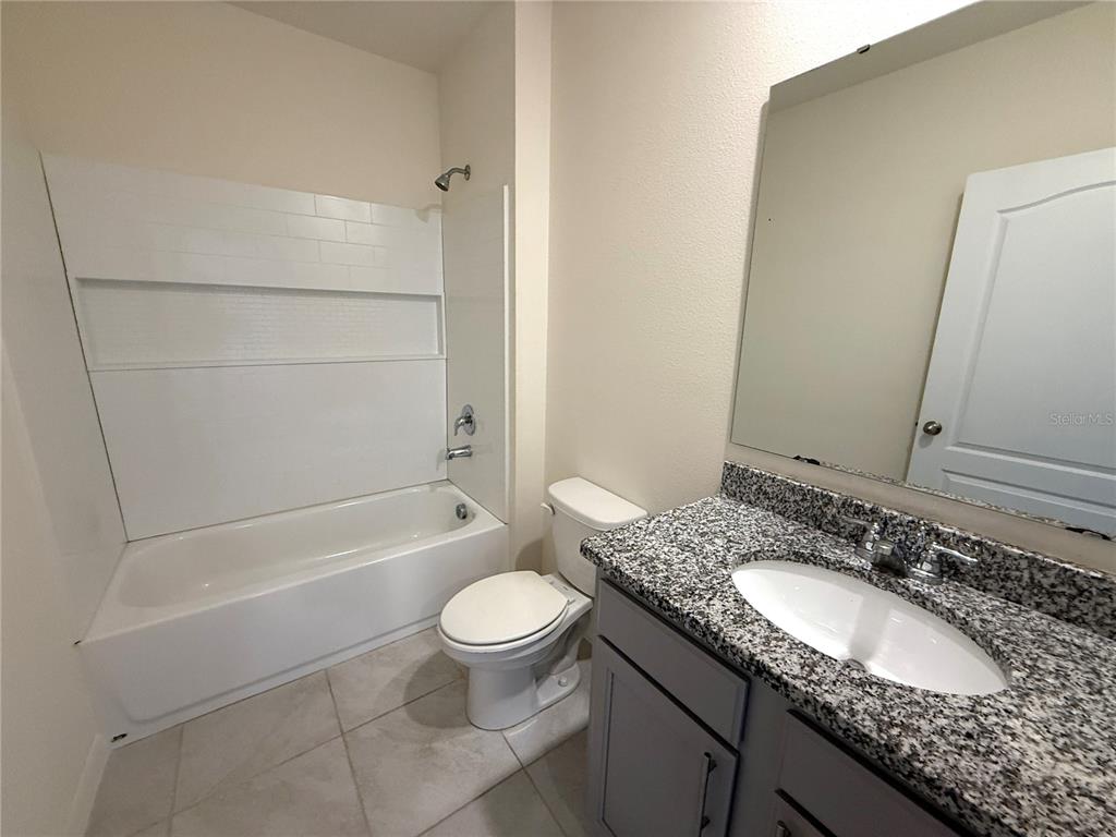 2877 Sunridge Loop St. Cloud, FL 34771 - Photo 16 of 19 a bathroom with a granite countertop sink toilet and shower