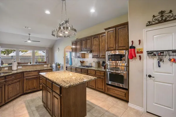 a kitchen with stainless steel appliances granite countertop a kitchen island a stove and a sink