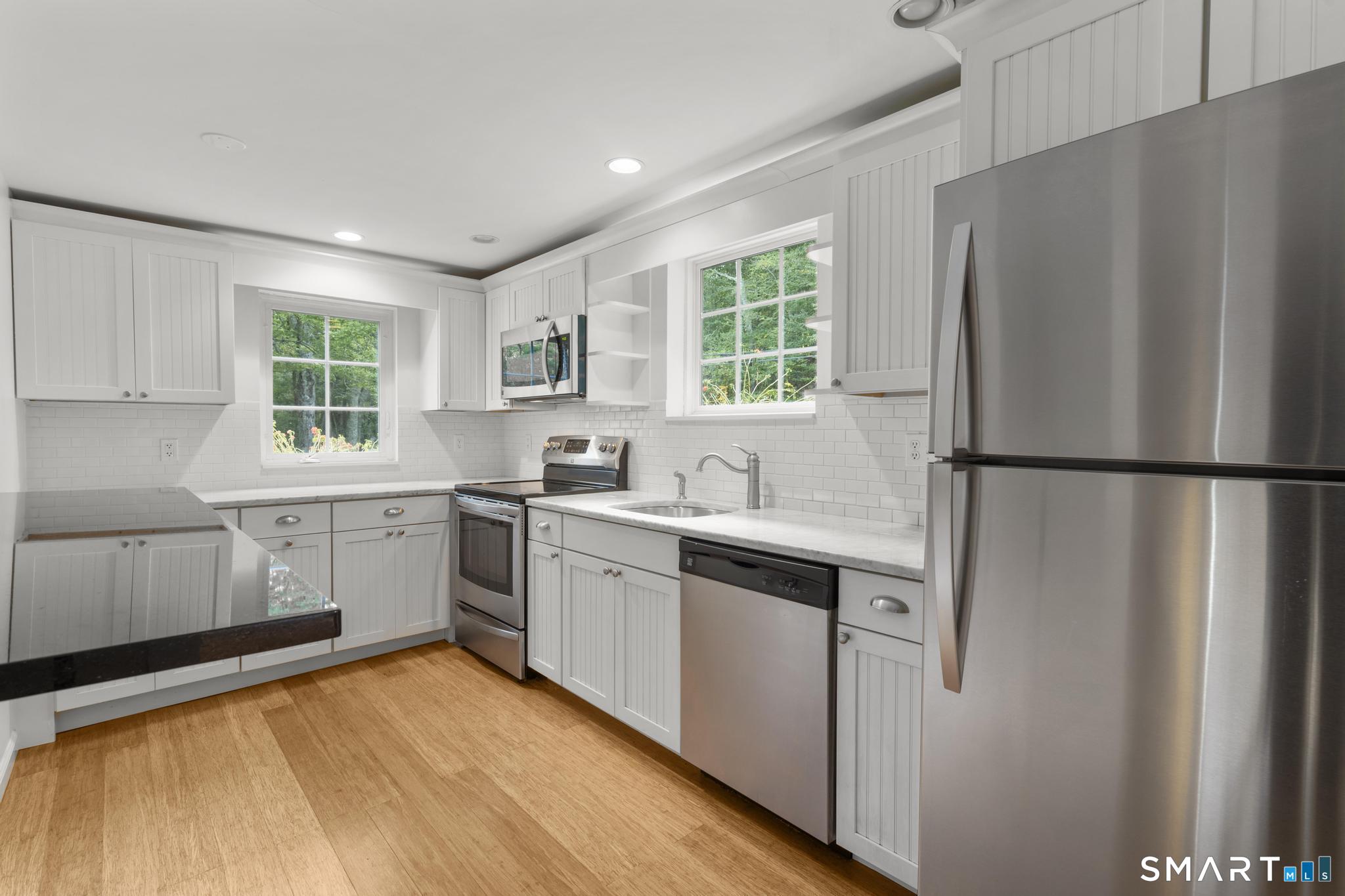 89 Book Hill Road Essex, CT 06426 - Photo 16 of 40 a kitchen with stainless steel appliances granite countertop a refrigerator a sink dishwasher a stove and white countertops with wooden floor